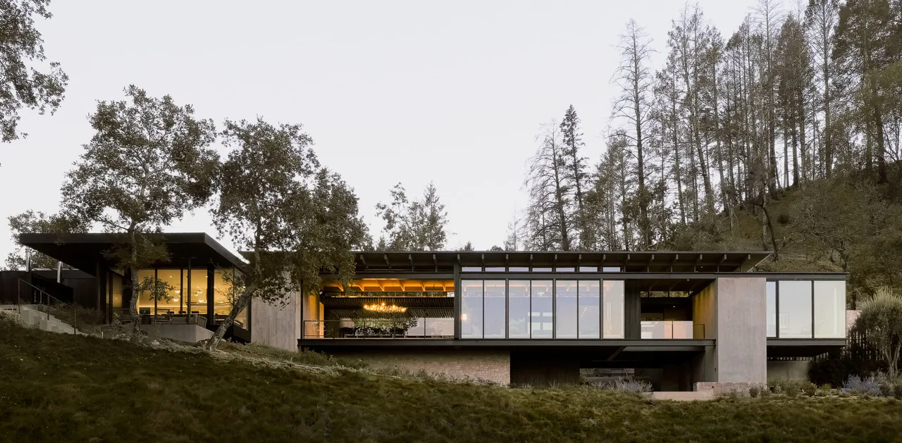 Exterior front view of Trestle Residence showing a modern one-story house with large floor-to-ceiling glass windows, flat roof with exposed-