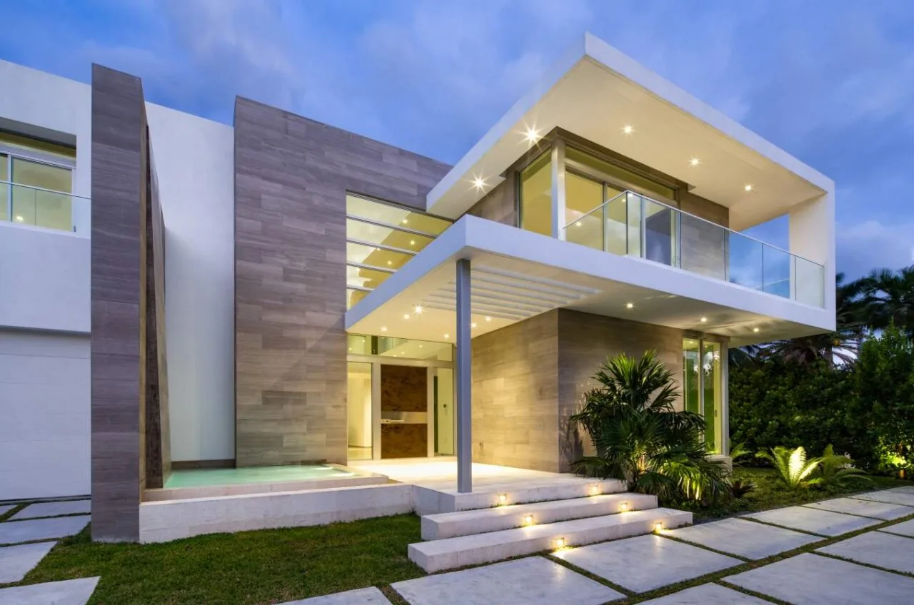 Modern two-story residence with cantilevered balcony and large glass windows at dusk.