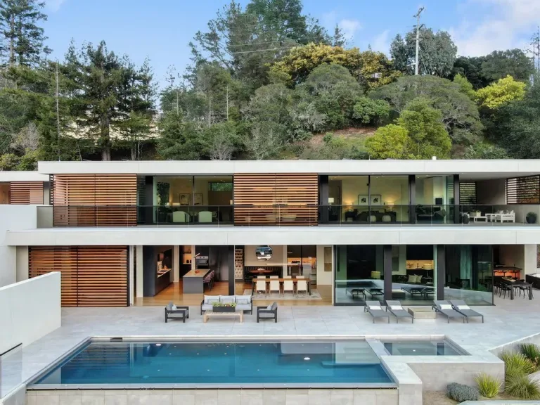 Two-story modern house with a flat roof and wooden slat screens next to a swimming pool.