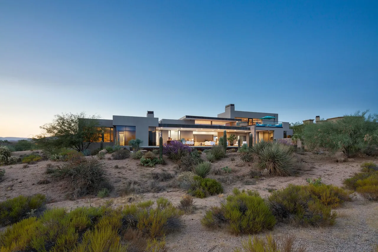 Modern home exterior at dusk with desert landscaping in front of the building.