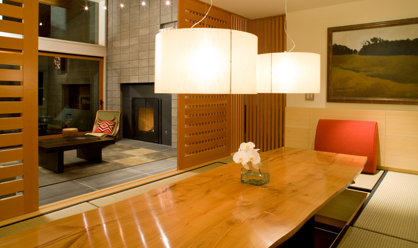 The Murray Hill Townhouse's dining area features a natural wood table and large pendant lights, with a separated living space including a fireplace.