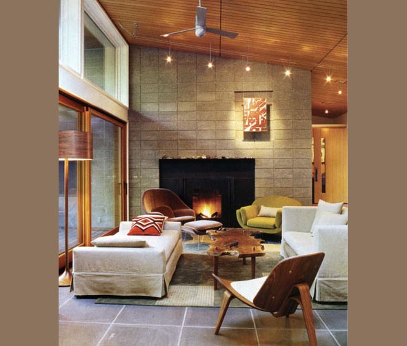Living room featuring a stone fireplace, wooden ceiling with spotlights, and midcentury modern furniture.