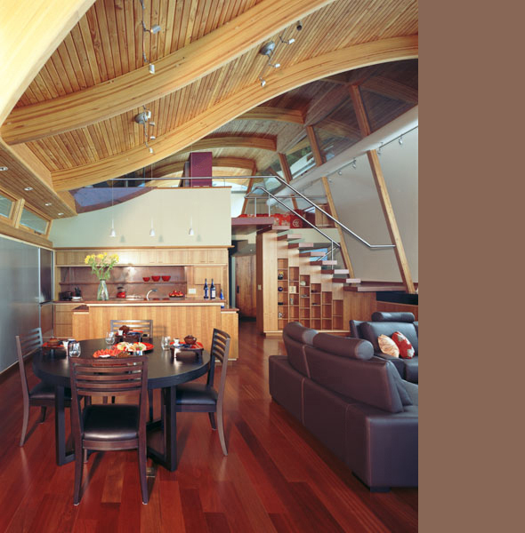 Open-plan living, dining, and kitchen space with wood ceiling and flooring in the Fennel Residence.