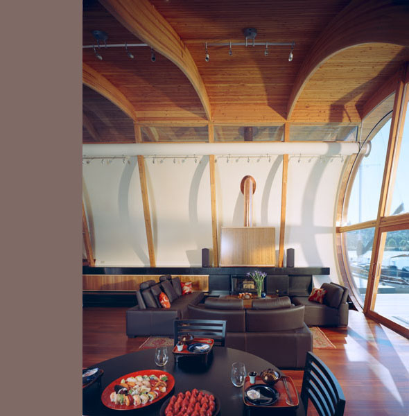 Living room features curved wooden vaulted ceiling and floor-to-ceiling glazing with curved supports.