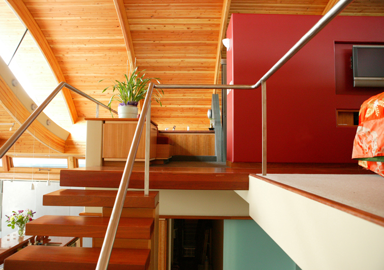 Wooden staircase and upper level with red accent wall and exposed wood ceiling.