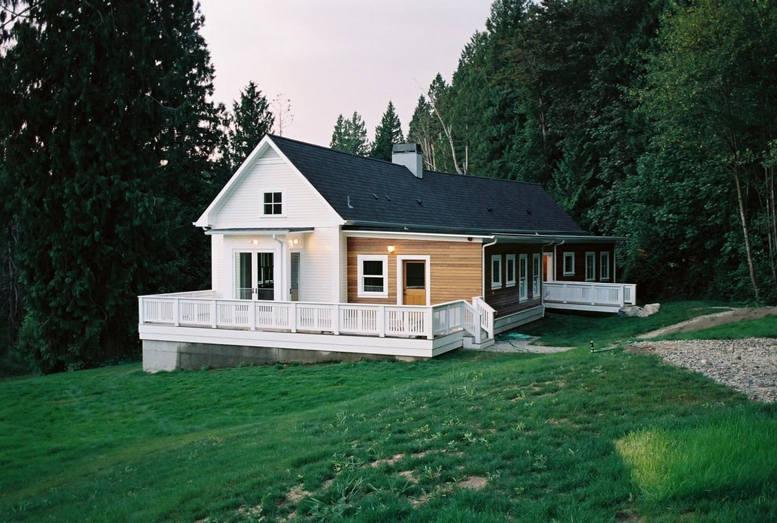 Harding Home exterior front and side view showing mixed white and wood siding and a black gable roof.