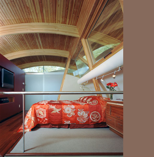 Bedroom interior featuring a curved wooden ceiling with exposed beams and angled floor-to-ceiling windows.
