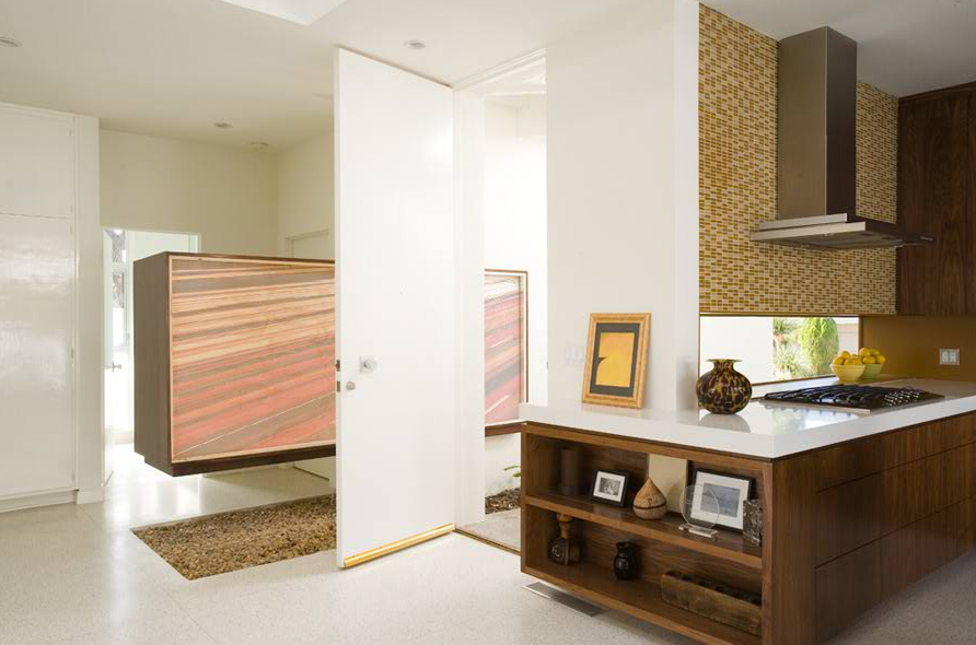 Modern kitchen interior with wooden cabinetry, a gas cooktop, and a mosaic tile backsplash behind the range hood.