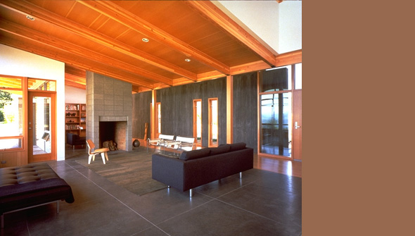 Living room featuring concrete flooring, wooden beam ceiling, and a concrete block fireplace wall.