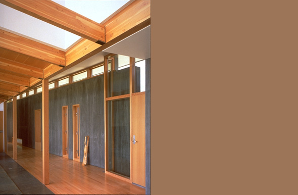 Hallway interior featuring exposed wood beams and floor-to-ceiling glazing above doors.