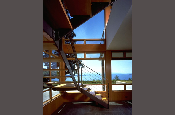 Interior of the Bruckner Residence showing a modern steel and wood staircase with large windows providing ample natural light and views.