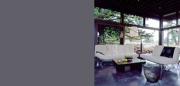 Living room with floor-to-ceiling glass walls overlooking an outdoor landscape on Decatur Island.