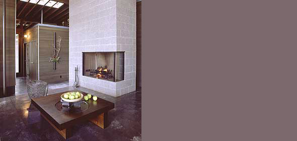 Living room featuring a fireplace set in a concrete block wall and a wooden coffee table with fruit.