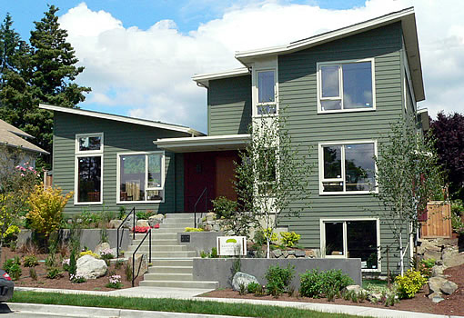 Modern two-story home with green horizontal wood siding and a shed roof design.