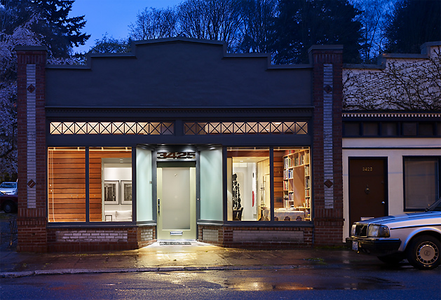 The Madrona Live/Work building features large street-facing windows and a central glass door, showcasing interior art and shelving.