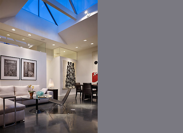 Interior view of a modern living and dining space featuring a triangular skylight and polished concrete floor.