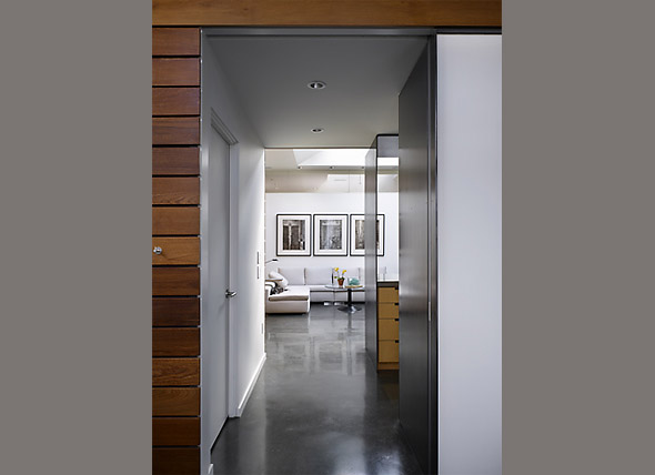 Interior view of a living room with polished concrete floors, three black and white framed artworks, and a minimalist color palette.