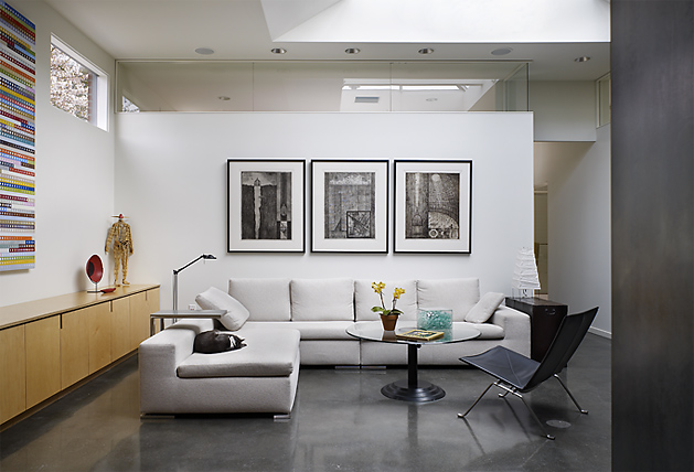 Living room in the Madrona Live / Work project by Tyler Engle Architects features a sectional sofa and polished concrete floor under a triangular skylight.