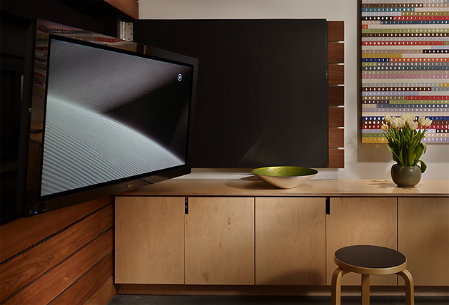 Interior featuring a flat screen TV on wood-paneled wall and a storage cabinet with decor items.