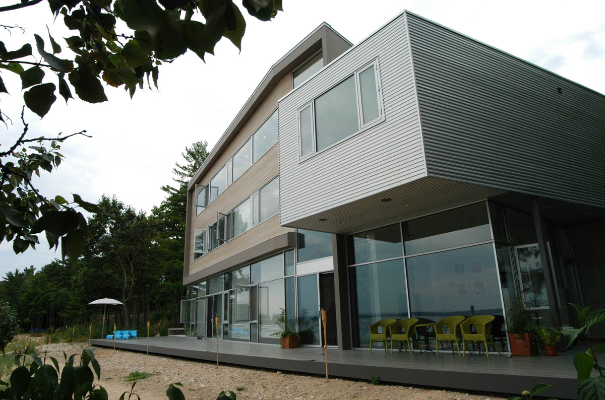 Exterior rear view of a modern multi-story residence with a combination of metal and wood siding and extensive glazing.