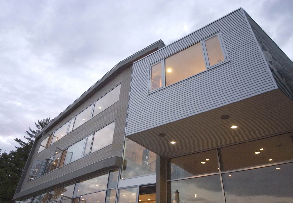 Exterior front view of the Michigan Residence showcasing extensive horizontal glazing and corrugated metal siding.