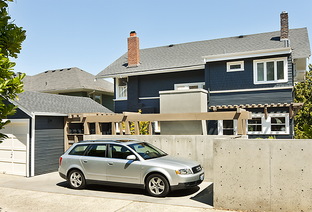 Mt Baker Courtyard features a blue clapboard house with a prominent concrete wall and detached garage.
