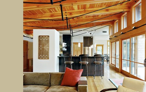 Mountain Meadow House interior features exposed wood ceilings and a kitchen island with black metal bar stools.