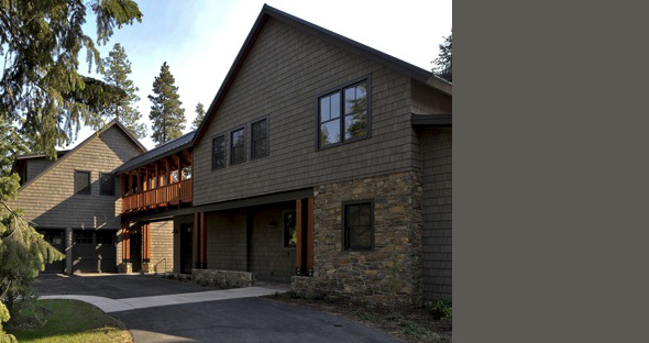 Mountain Retreat exterior showing gray shingle siding, stone base, and covered balcony, designed by Clinkston Brunner Architects.