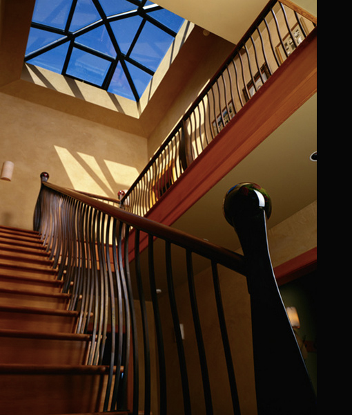 Interior staircase with curved metal balusters and a geometric skylight overhead.