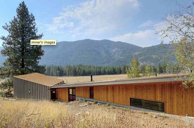 Miner's Refuge features a wood and metal exterior along a grassy field with forest backdrop.