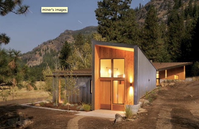 Miner's Refuge features a modern metal siding exterior with a recessed wood-paneled entry in a mountain forest setting.