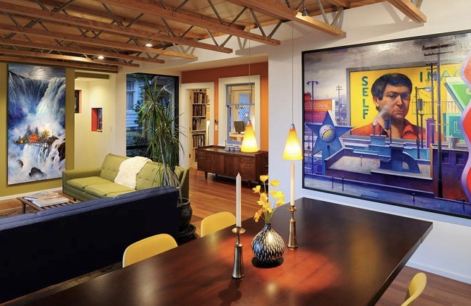 Living and dining space with exposed wooden truss ceiling and large colorful paintings, featuring modern pendant lighting and mixed seating.