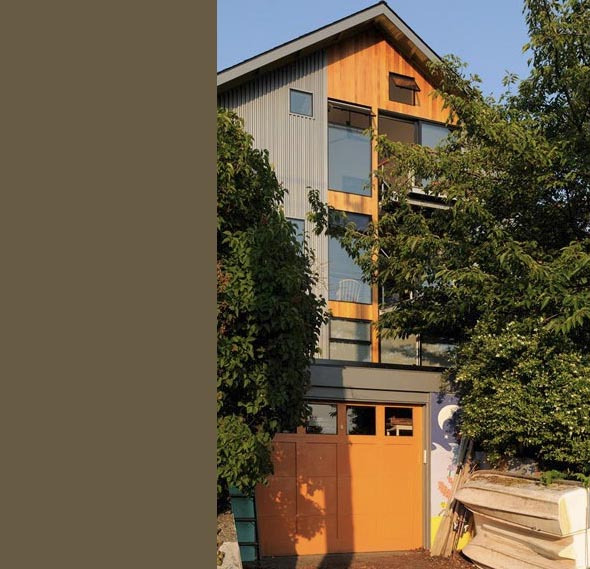 Modern home exterior featuring wood and metal siding with large windows and a gable roof.