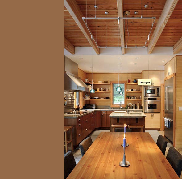 Kitchen with wooden cabinets, a central island, exposed wood beams, and pendant lights above the dining table.
