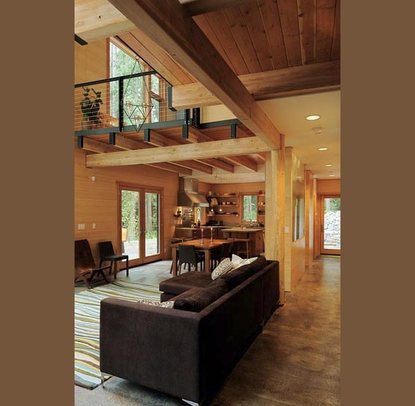 Open living and kitchen area with wood finishes and a mezzanine with cable railing above.