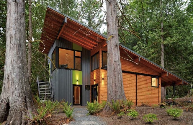 Schell-Wheeler project features a wood and metal exterior with large windows, nestled among tall trees in Seattle.