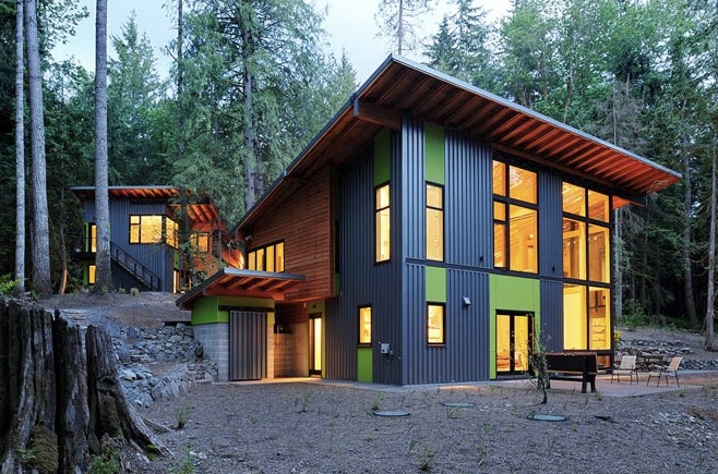 The Schell-Wheeler house features mixed siding colors and large windows nestled in a forest setting.