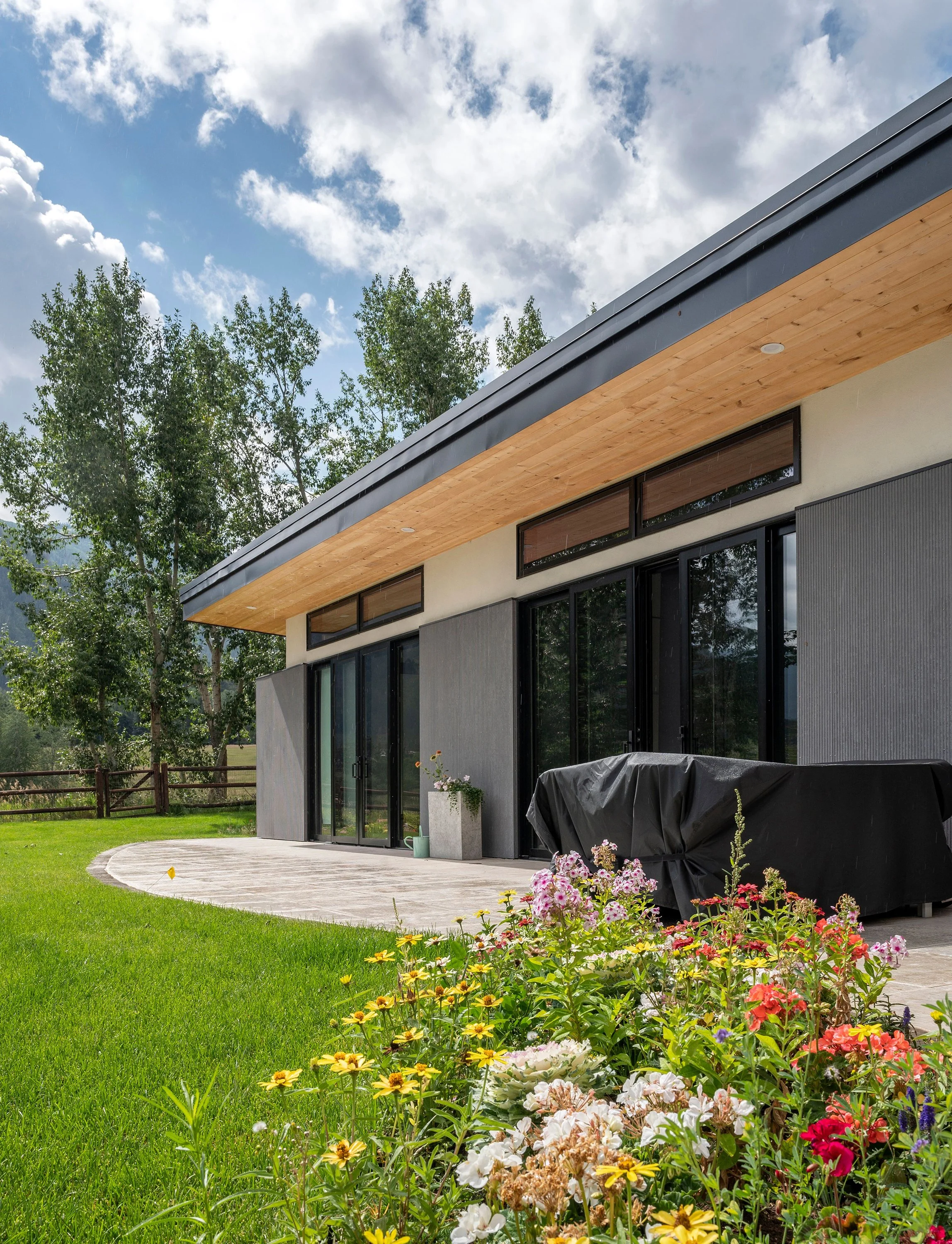 Meadowood Guesthouse features a covered patio with wood soffit and gray exterior panels in a landscaped setting.