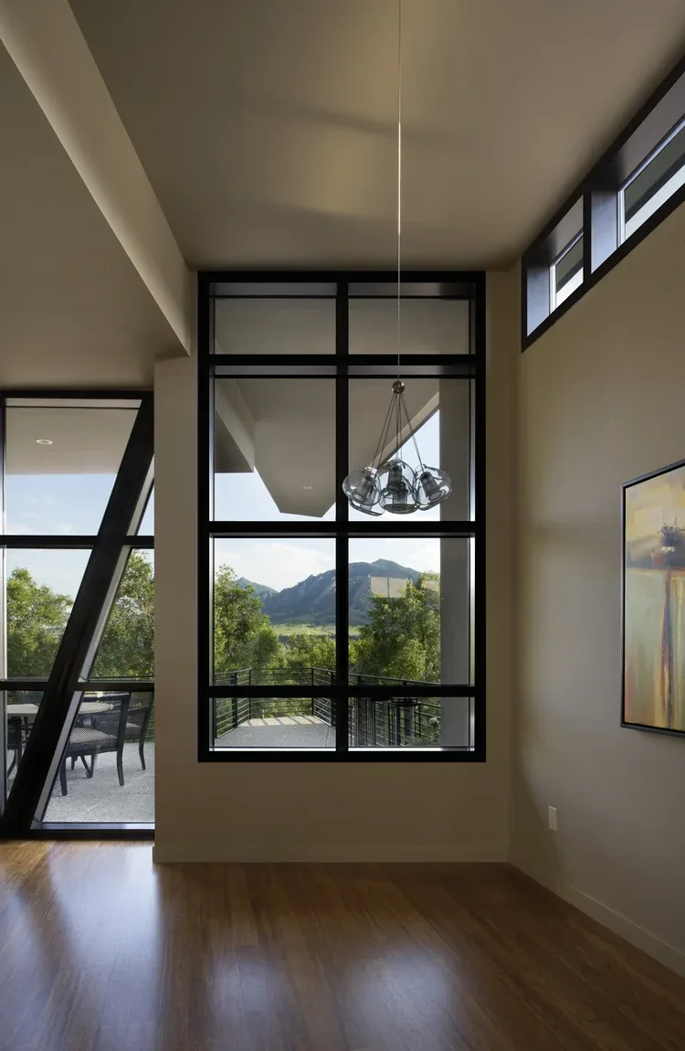 Room interior with large black-framed windows and a view of mountains through the glass.