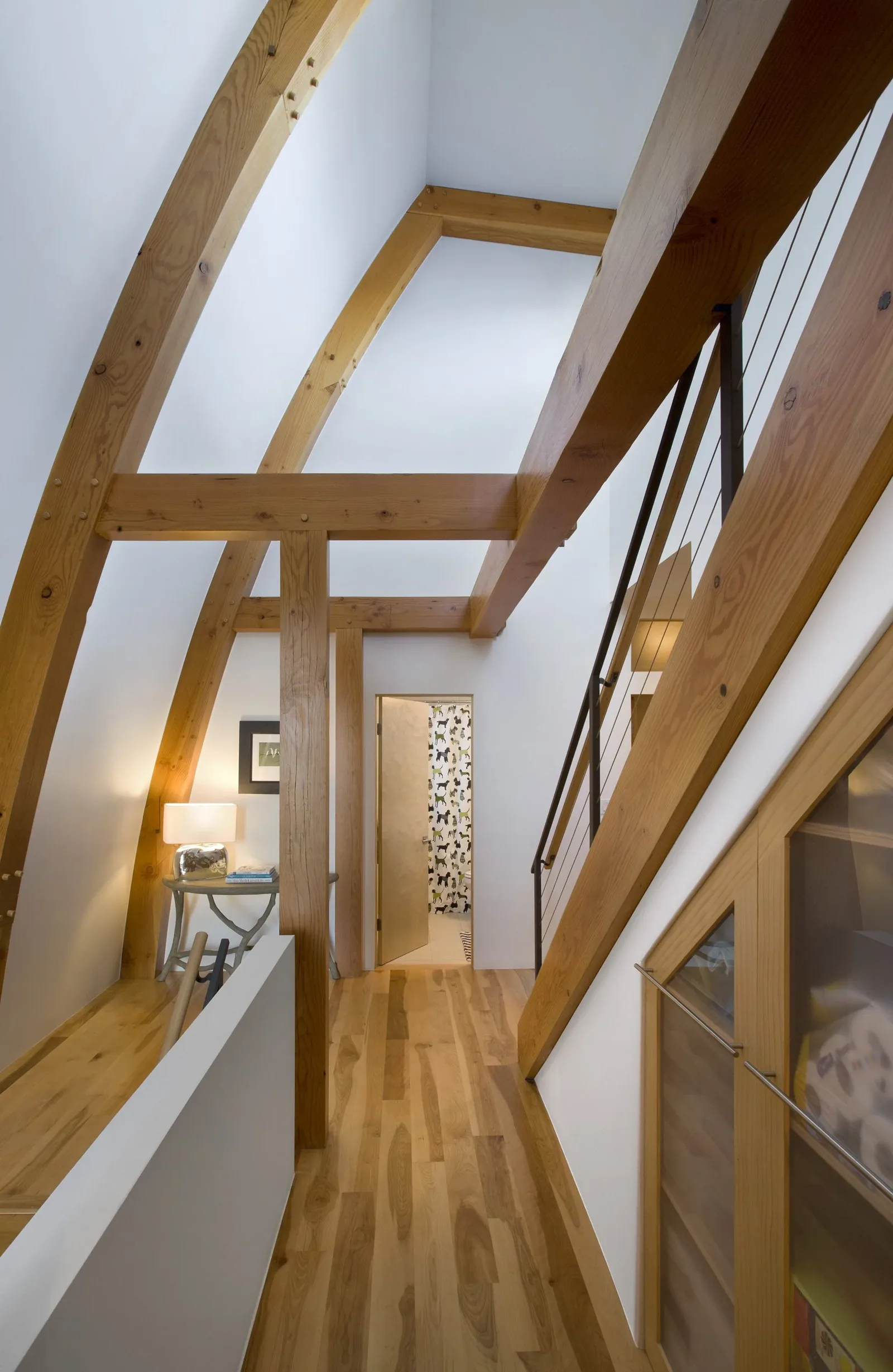 Hallway featuring exposed wooden beams and a polished hardwood floor in a modern residential interior.