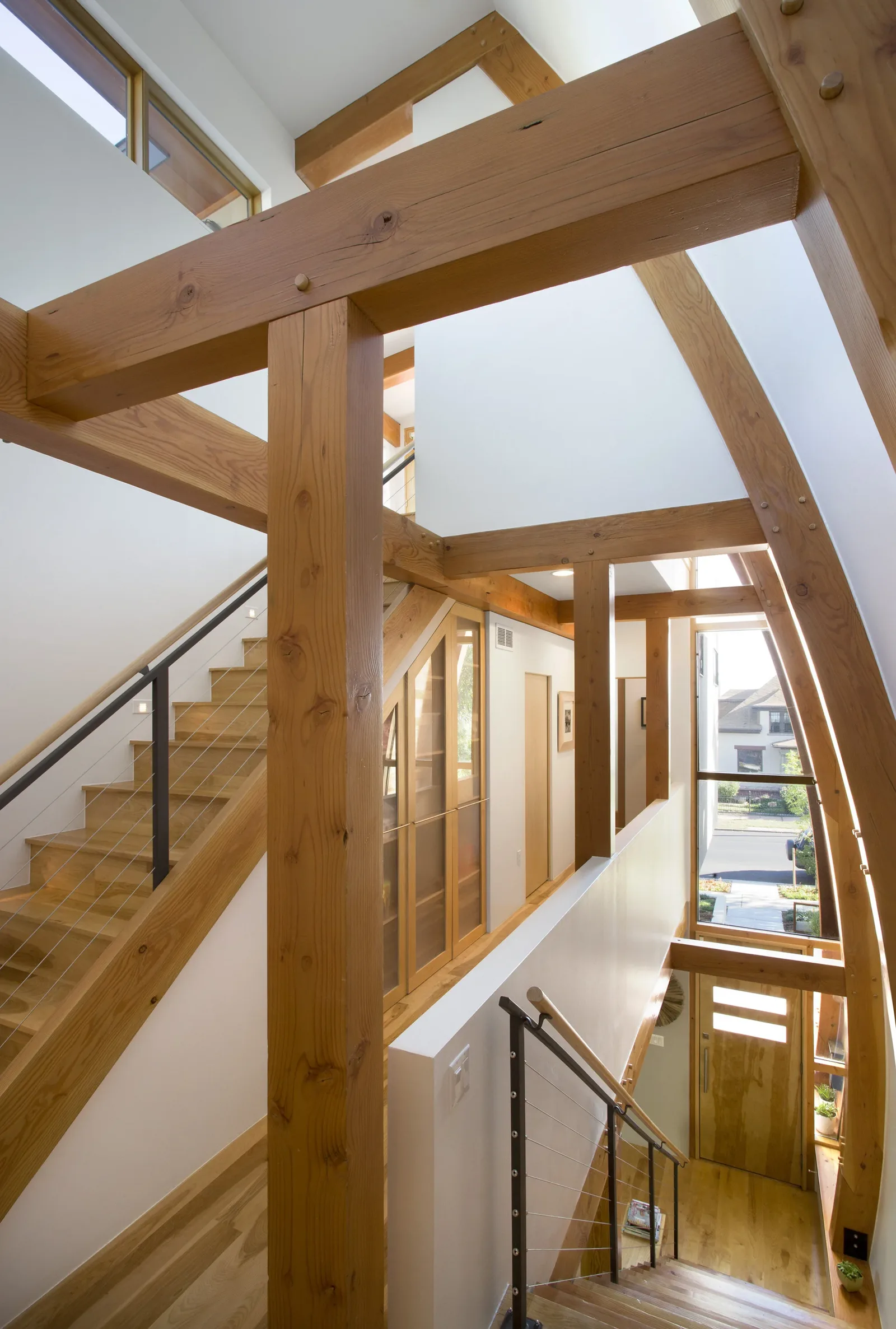 View of the stairwell showcasing exposed wood beams and natural light from the entry window.