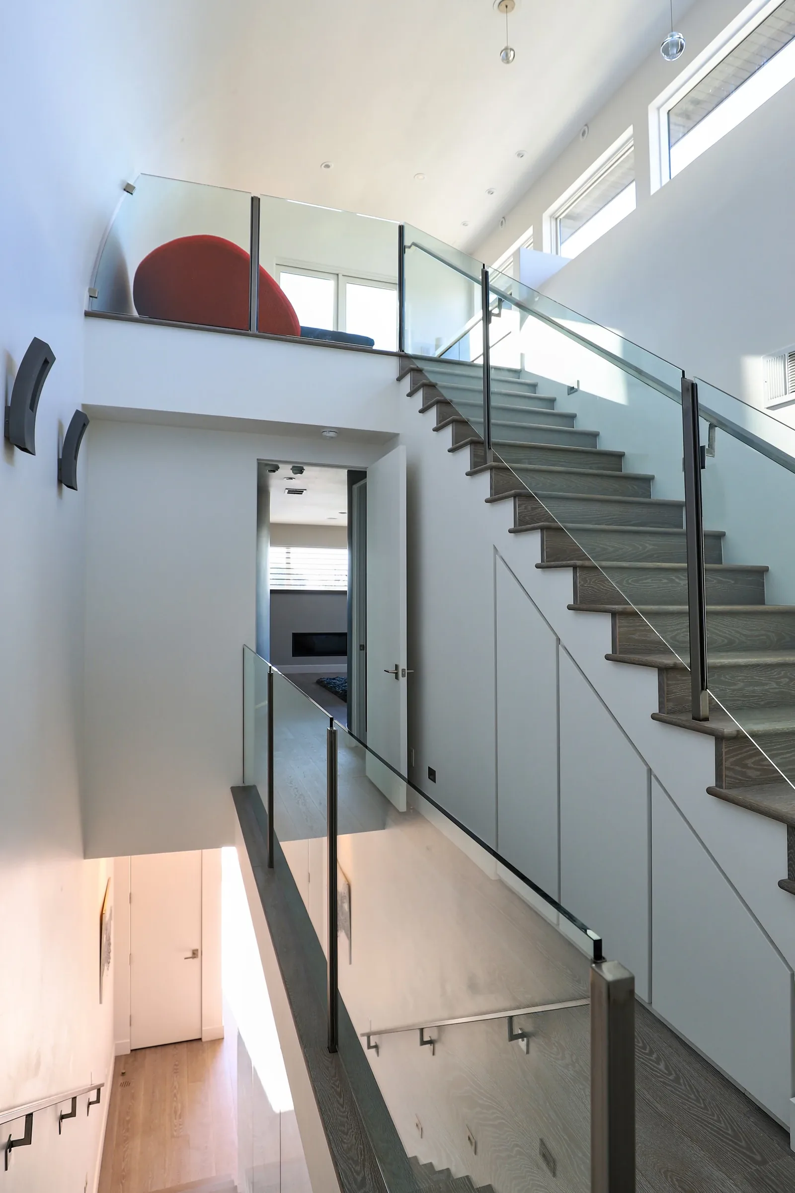 Modern staircase with glass railing and clerestory windows in a residential interior.