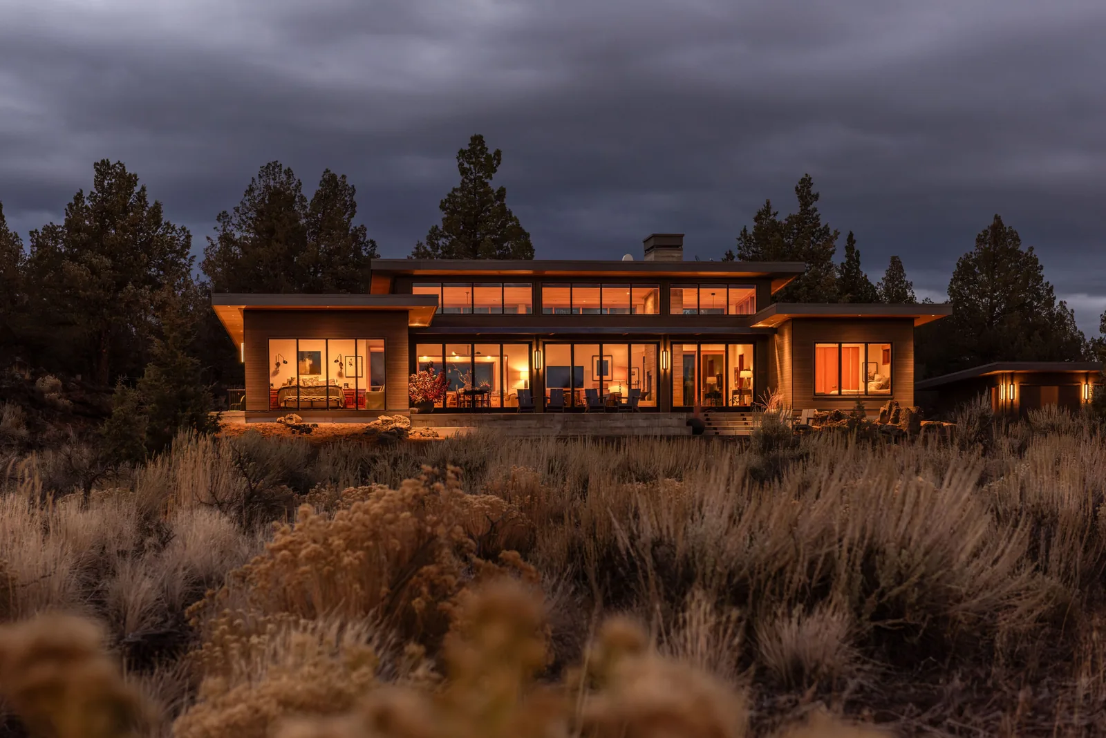 Deschutes Modern Oasis by Emerick Architects is a modern home featuring extensive glazing and flat roof design in a natural desert setting.