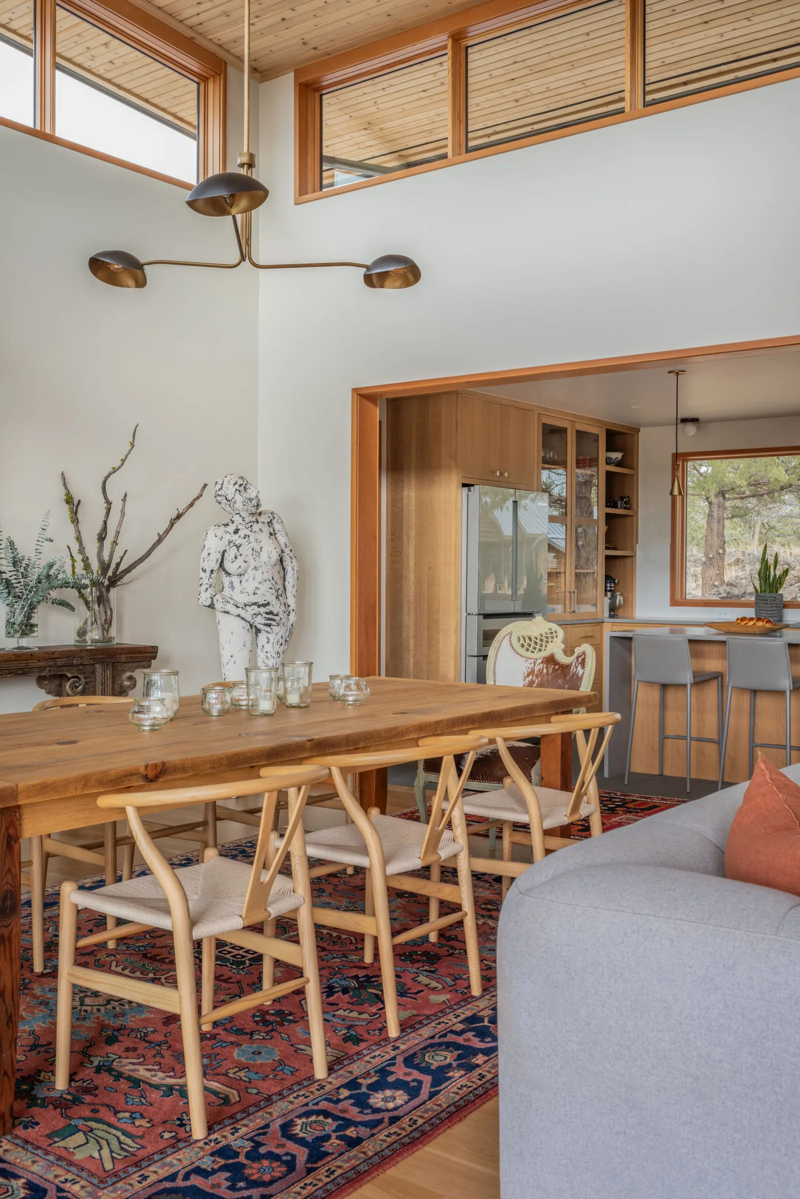 Dining room and kitchen area with wood ceilings, a variety of seating styles, and natural light from clerestory windows.