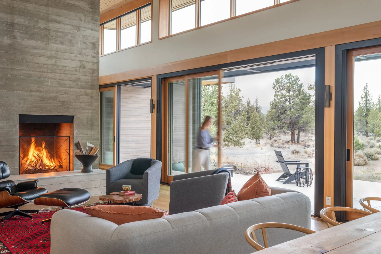 Living room with a concrete fireplace and large sliding glass doors facing a desert landscape in the Deschutes Modern Oasis project.