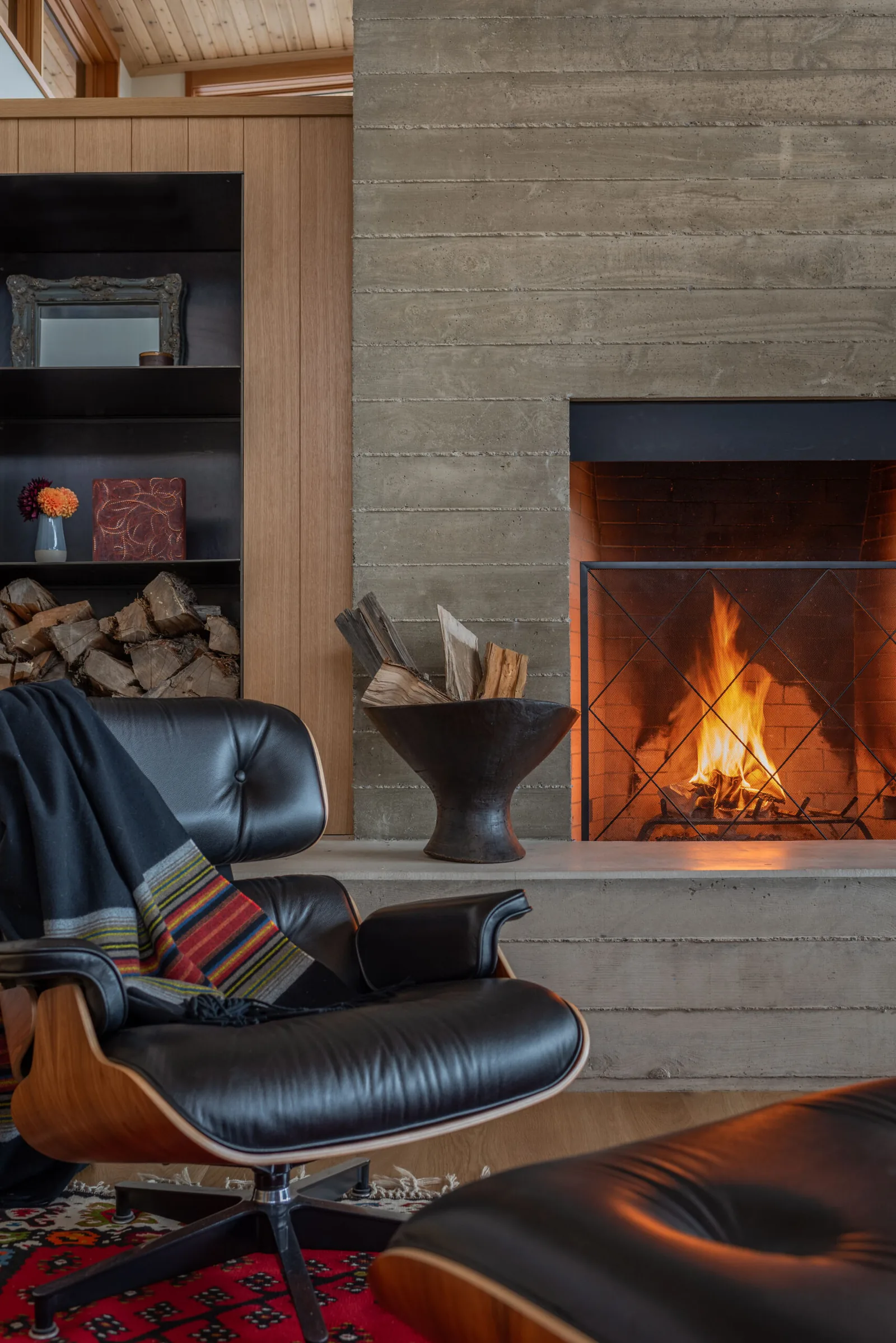 DESCHUTES MODERN OASIS project by Emerick Architects features a concrete fireplace and black leather lounge chair in the living room.