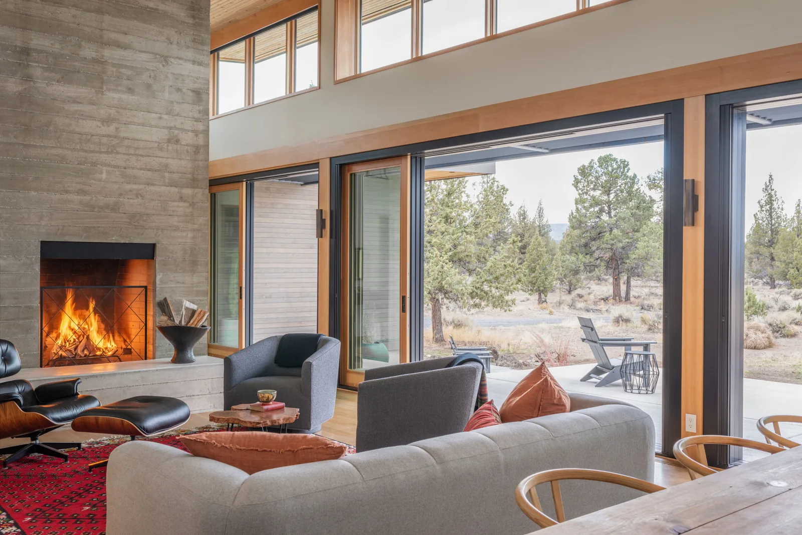 Living area in Deschutes Modern Oasis with concrete fireplace, wood ceiling planks, and large sliding glass doors to outdoor space.