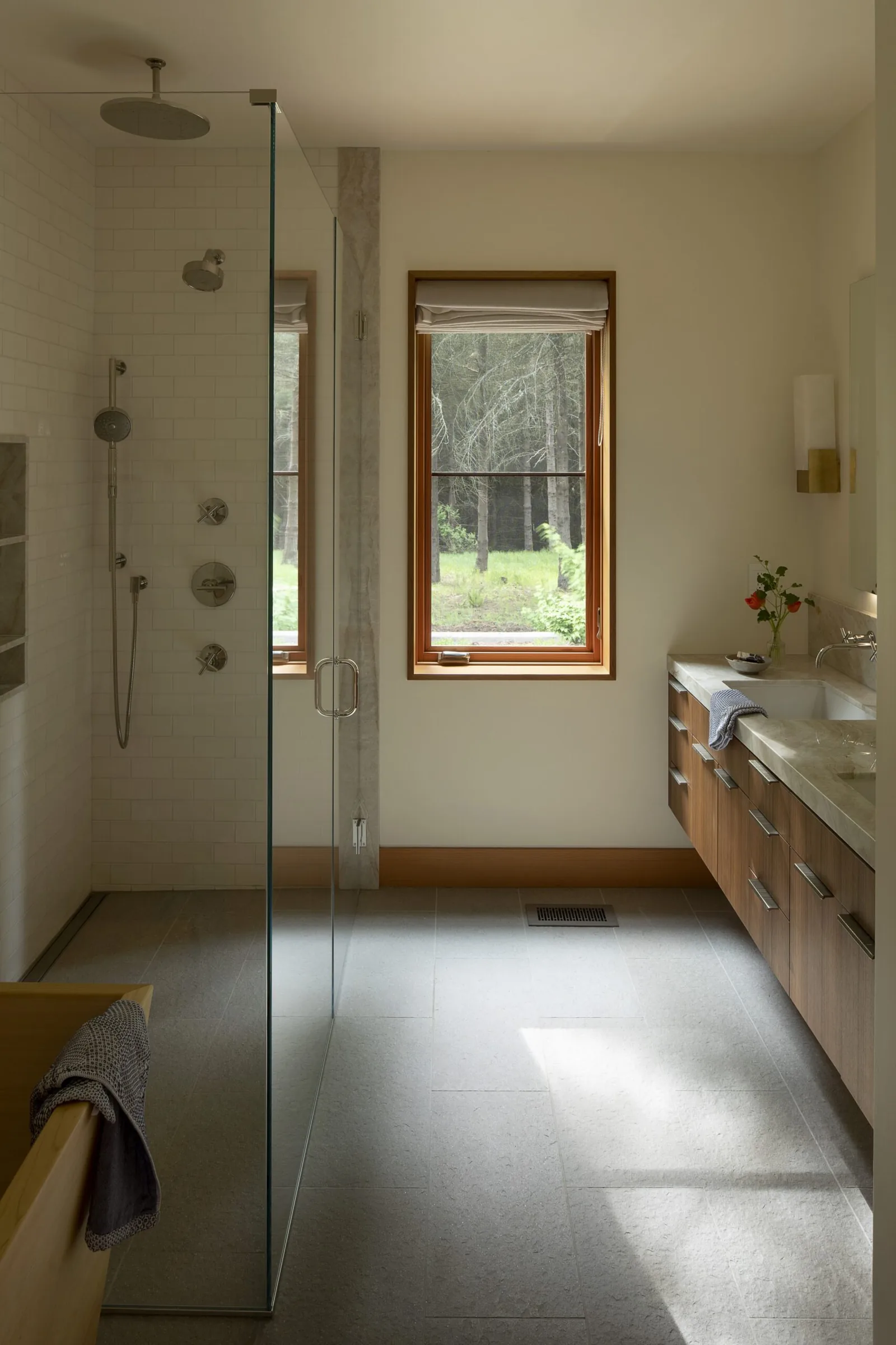 Bathroom featuring a glass shower enclosure, a wood-framed window, and a wood vanity with stone countertop.