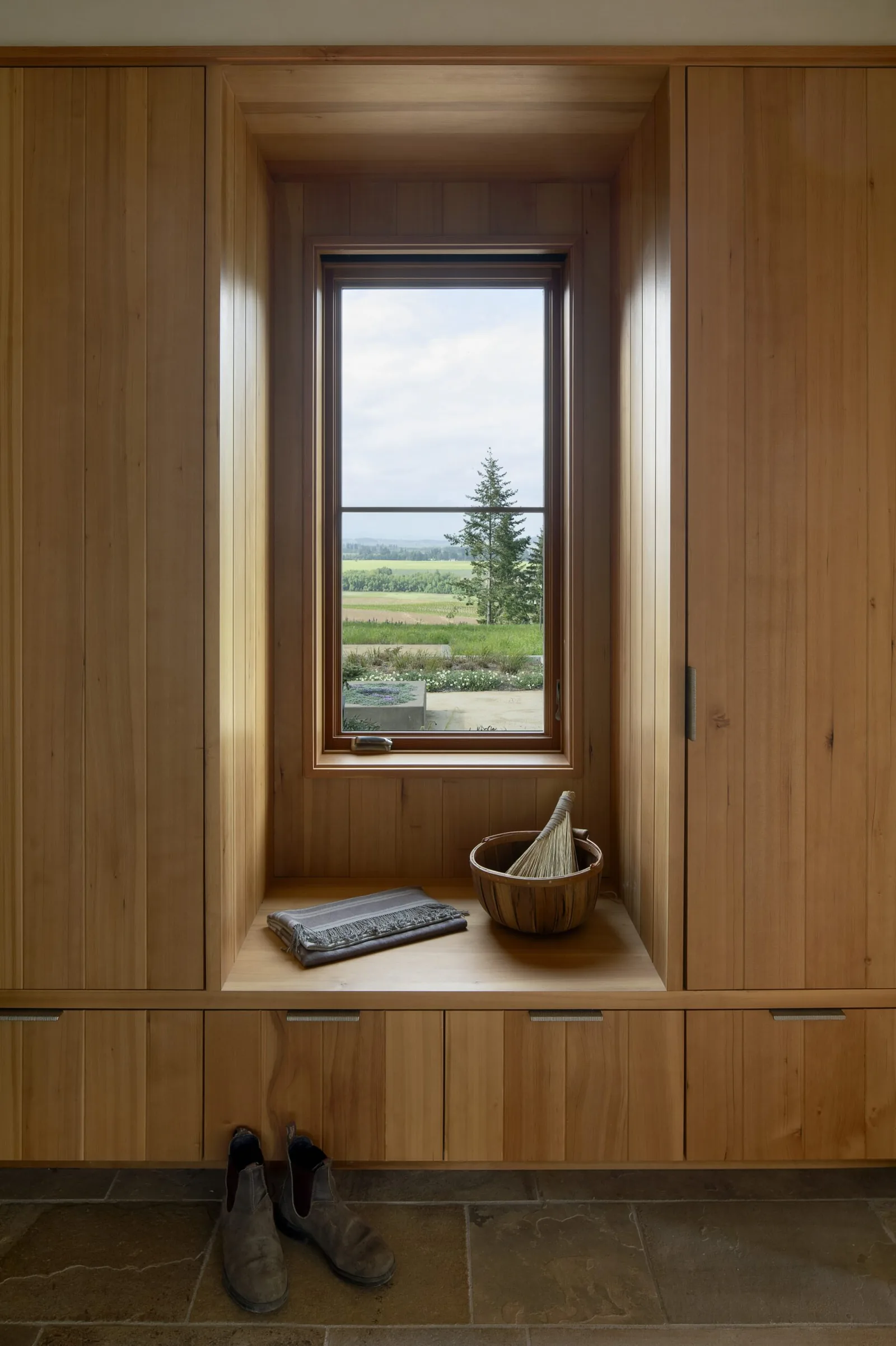 Mudroom features wood paneling, built-in bench and cabinets, and a window with vineyard view.
