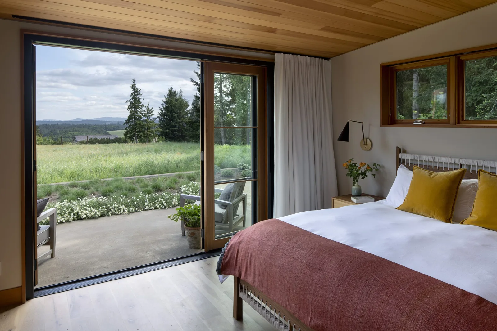 Bedroom features floor-to-ceiling sliding glass door with view to patio and landscape.